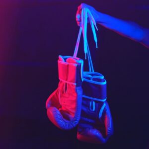 Red boxing gloves, ring with red and blue lights, industrial gym. selective focus