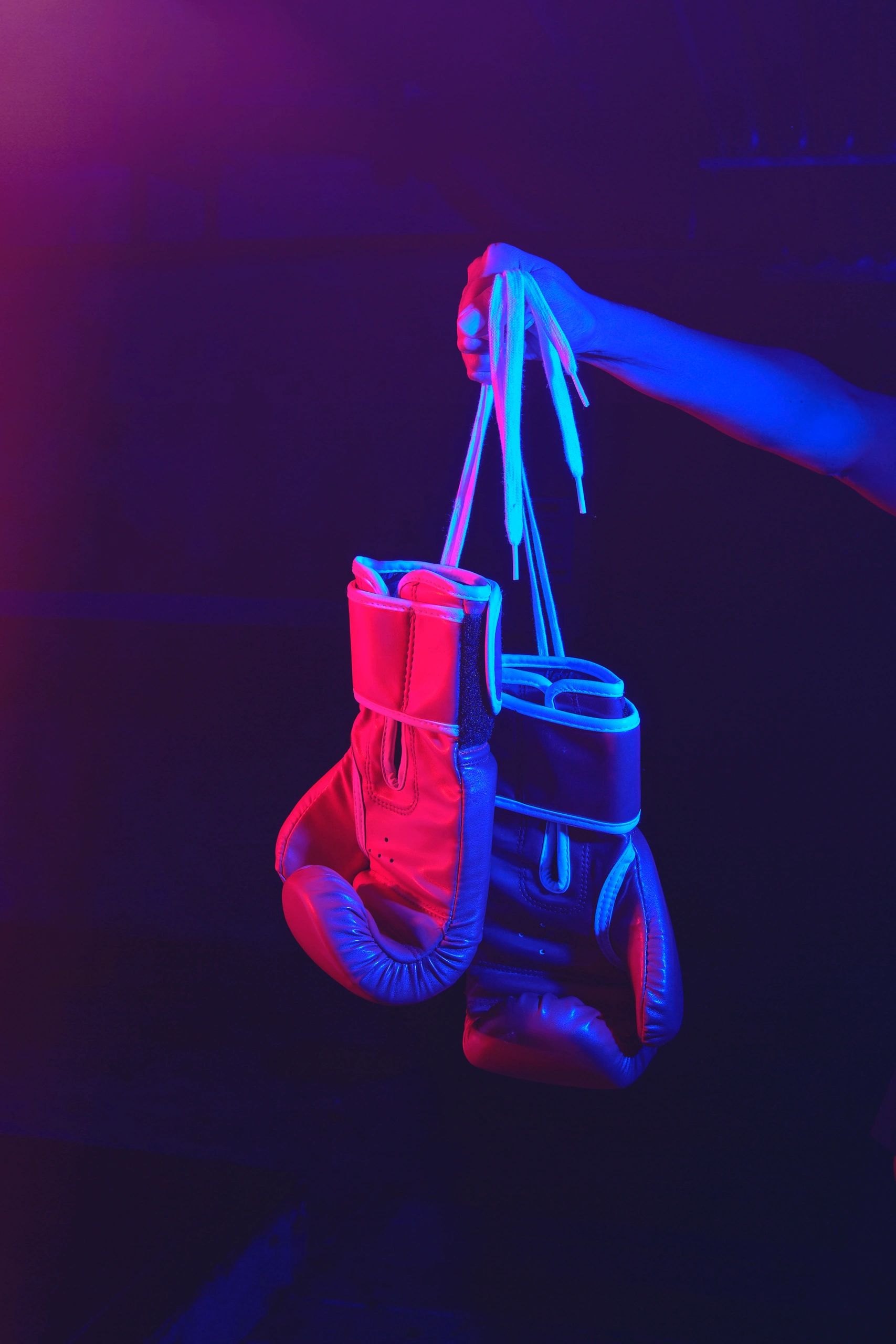 Red boxing gloves, ring with red and blue lights, industrial gym. selective focus